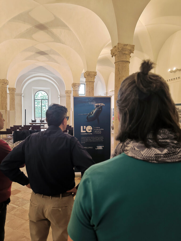 Persone guardano il primo pannello della mostra L'eredità della vita presso Domus Pauperum a Perugia