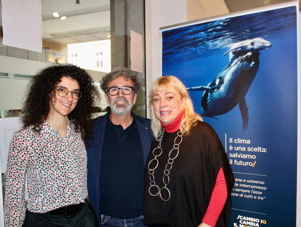 Tre persone posano davanti al pannello introduttivo della mostra “L’eredità della vita. Il clima è una scelta: salviamo il futuro” durante l’inaugurazione a Gorizia.