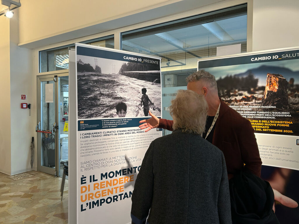 Due persone osservano i pannelli informativi della mostra “L’eredità della vita” dedicati agli effetti del cambiamento climatico.
