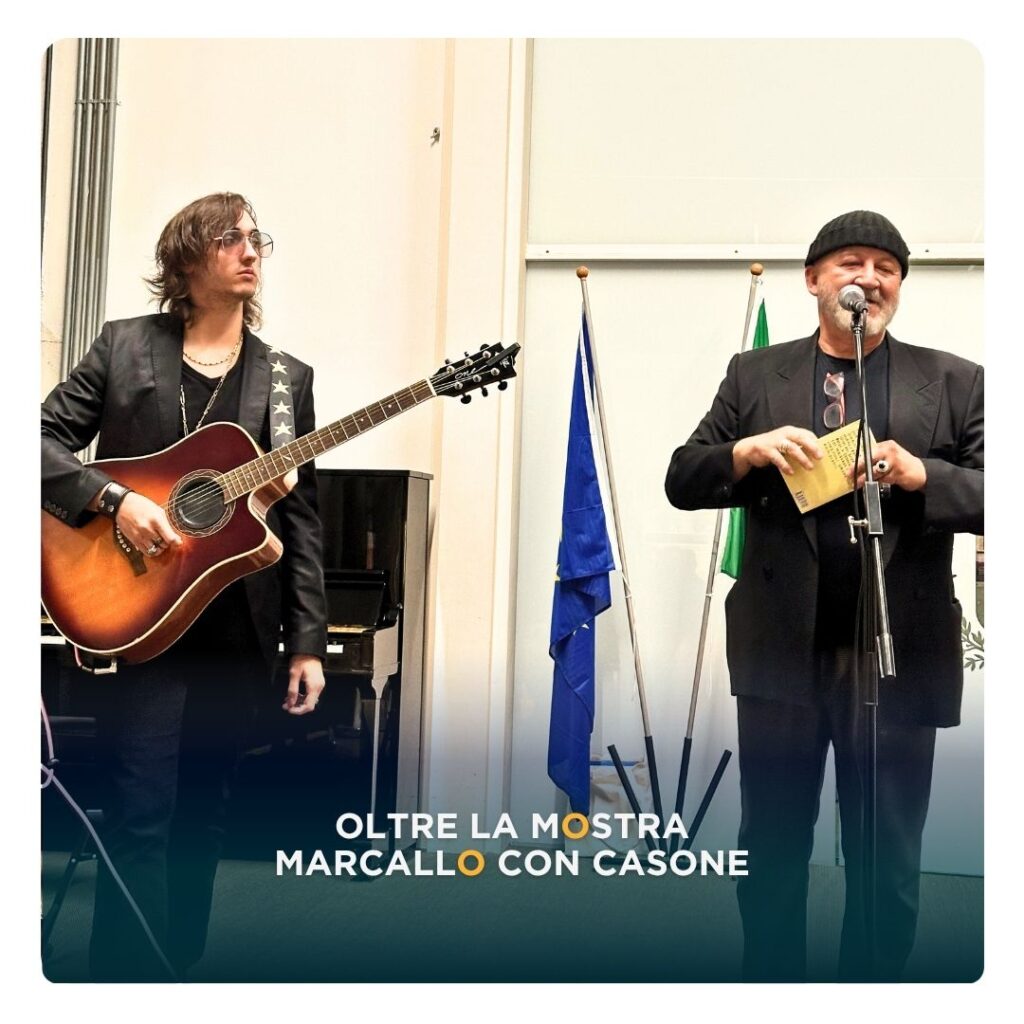 Un musicista con chitarra acustica e un uomo al microfono aprono l’evento della mostra “L’eredità della vita” a Marcallo con Casone.