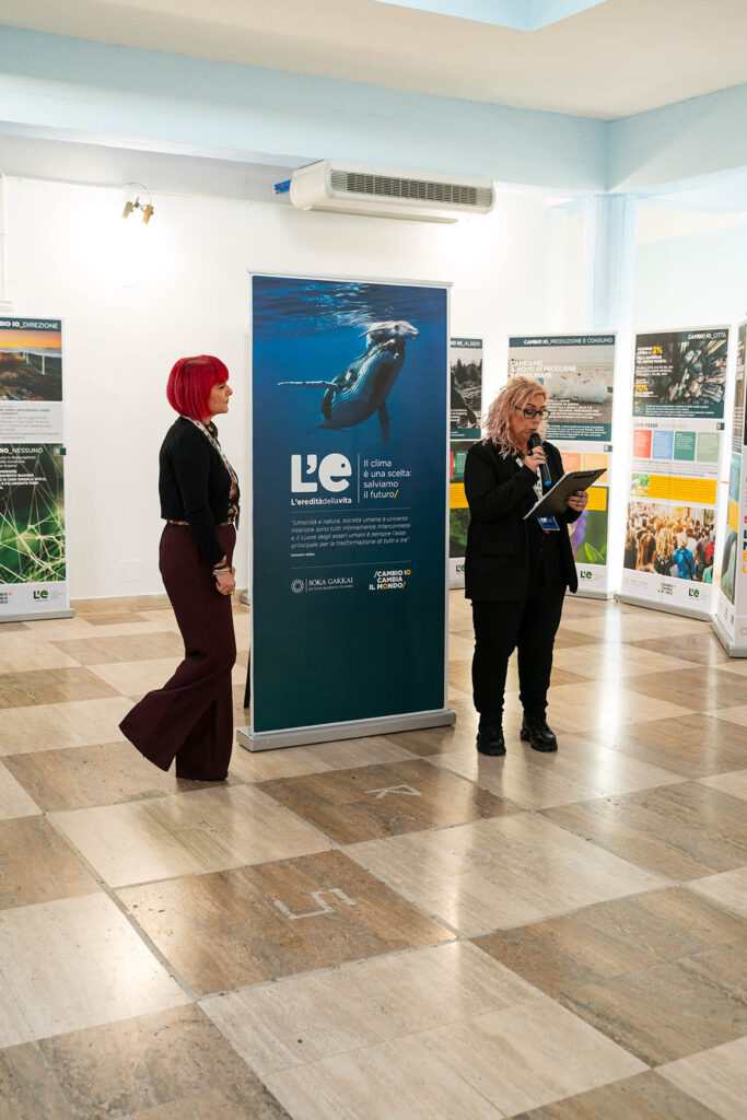 Due persone parlano davanti ai pannelli espositivi della mostra “L’eredità della vita. Il clima è una scelta: salviamo il futuro”, all’interno della Sala della Cultura di Guidonia Montecelio.