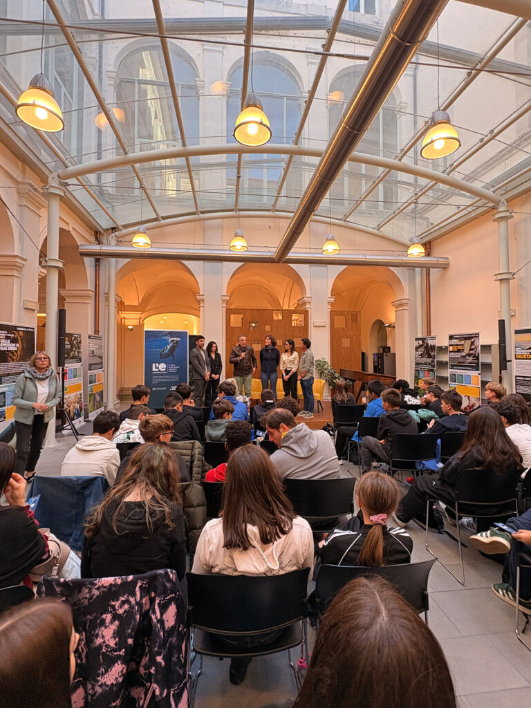 pubblico di giovani ascoltano una conferenza di inaugurazione della mostra l'eredità della vita