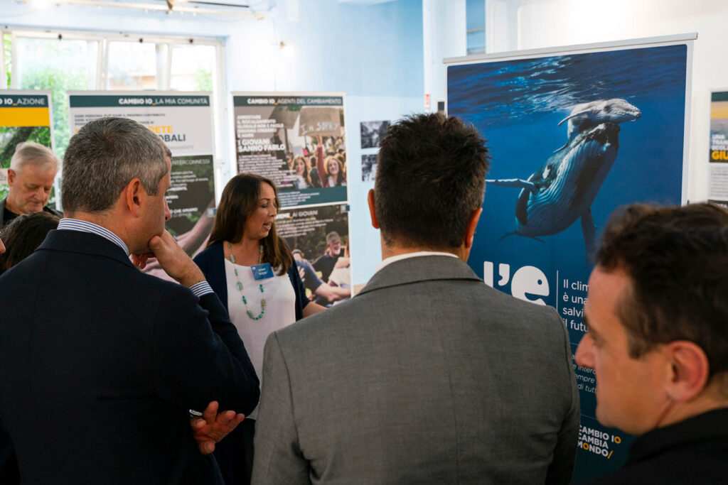 Un gruppo di visitatori ascolta una guida che illustra i pannelli della mostra “L’eredità della vita” a Guidonia Montecelio.