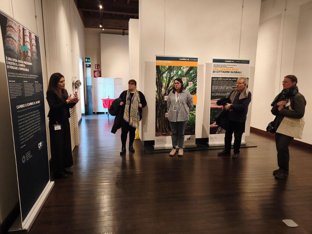 Una donna spiega un pannello della mostra "L'eredità della vita" in linguaggio LIS. 