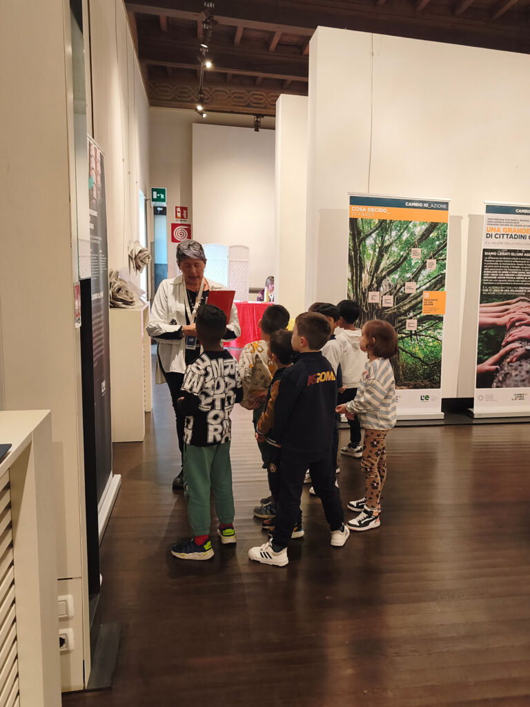 bambini visti di spalle davanti un pannello durante una visita della mostra "L'eredità della vita"
