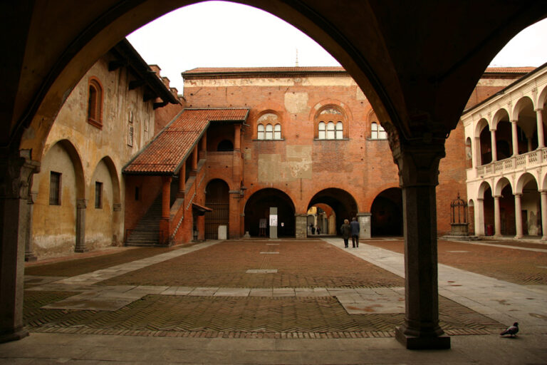 Cortile interno del Broletto di Novara, con portici ad archi e edifici storici in mattoni che circondano la piazza centrale.