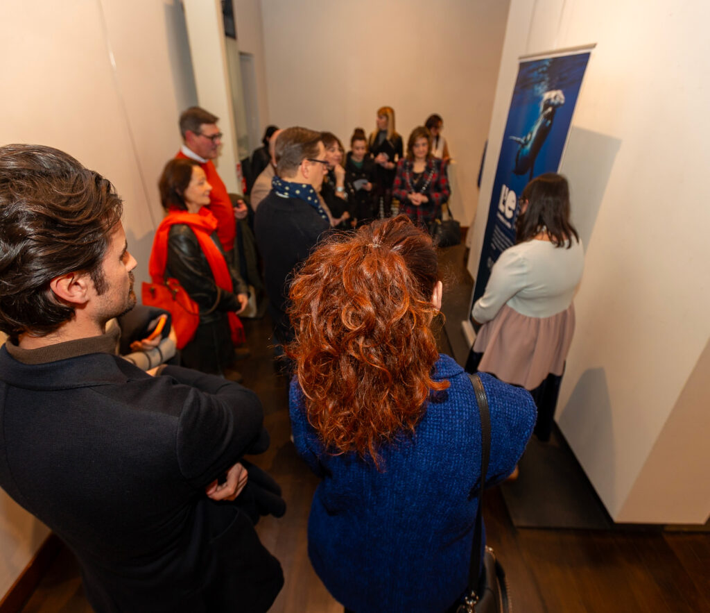 Piccolo gruppo di visitatrici e visitatori ascolta una spiegazione davanti a un pannello espositivo della mostra.