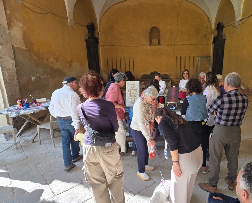 Gruppo di persone guardano un tavolo su cui sono poggiate opere d'arte fatti con oggetti riciclati 