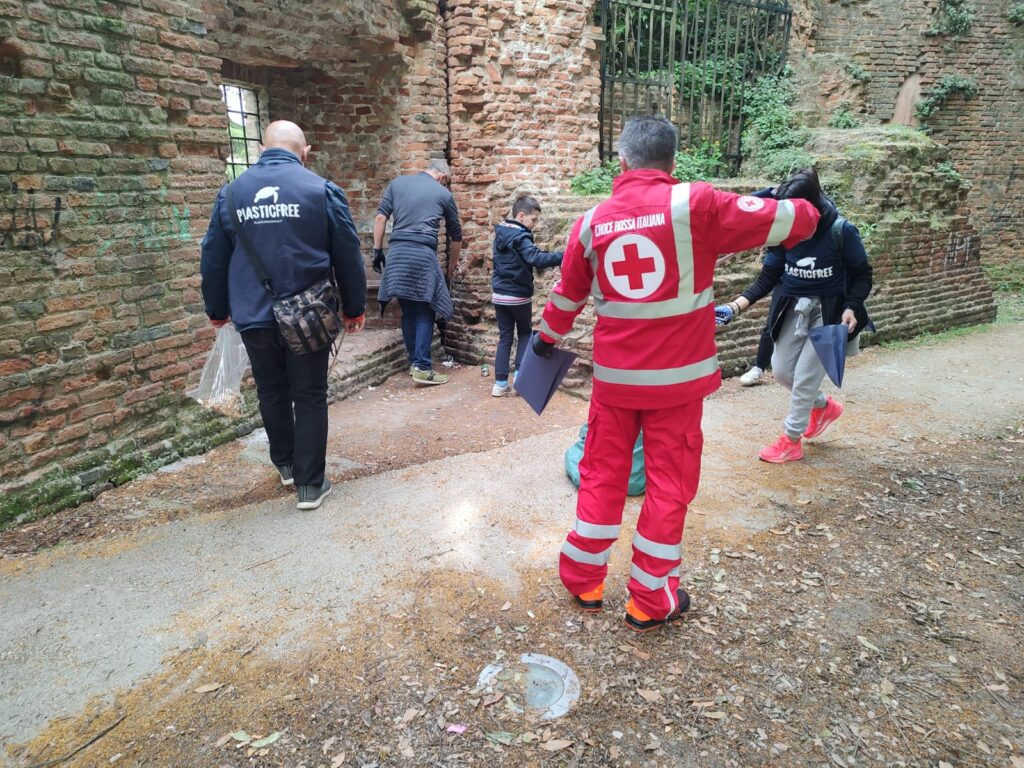 Gruppo di persone raccolgono cicce di sigarette dalla strada guidati dalla Croce Rossa