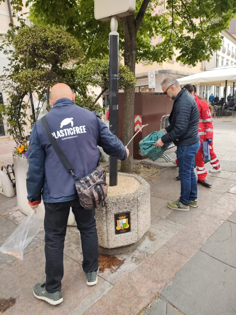 Gruppo di persone raccolgono cicce di sigarette dalla strada guidati dalla Croce Rossa