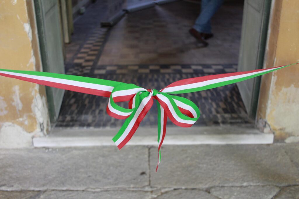 Nastro tricolore annodato all’ingresso della mostra allestita in una dimora storica.