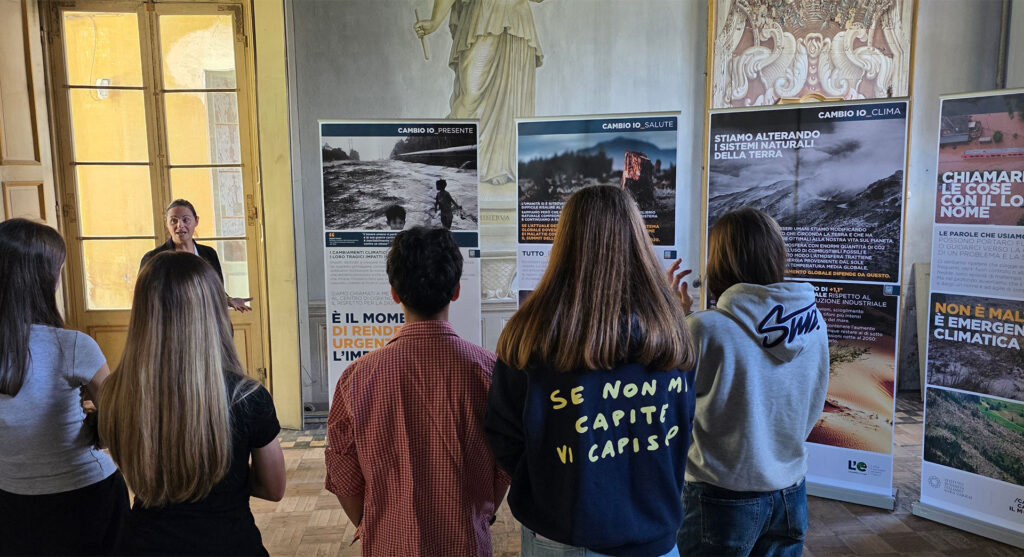 Gruppo di giovani partecipa a una visita guidata tra i pannelli sul cambiamento climatico.