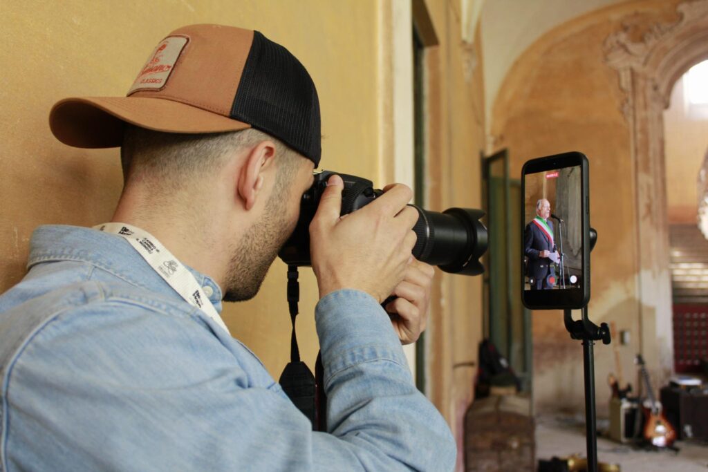 Fotografo riprende con una fotocamera un intervento durante l’inaugurazione della mostra.